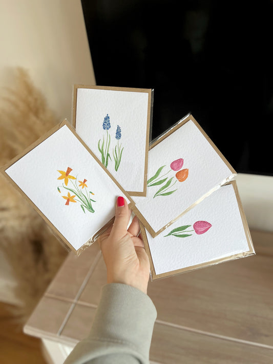 A set of 4 glittery cards including hand painted watercolour illustrations such as daffodils, tulips, a single tulip and muscari. 